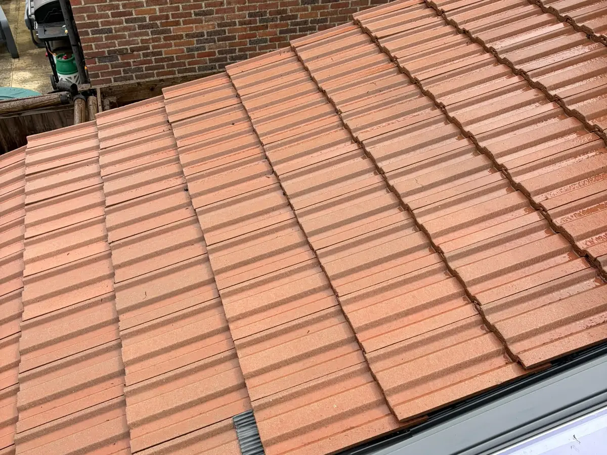 Red concrete tiles around a roof window after cleaning